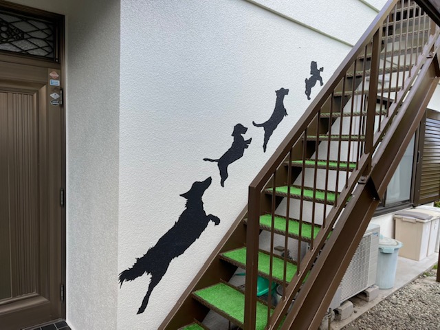 外階段の外壁に犬が4匹駆け上っているアート塗装の写真
